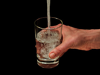 ein Glas wird mit Trinkwasser gefüllt